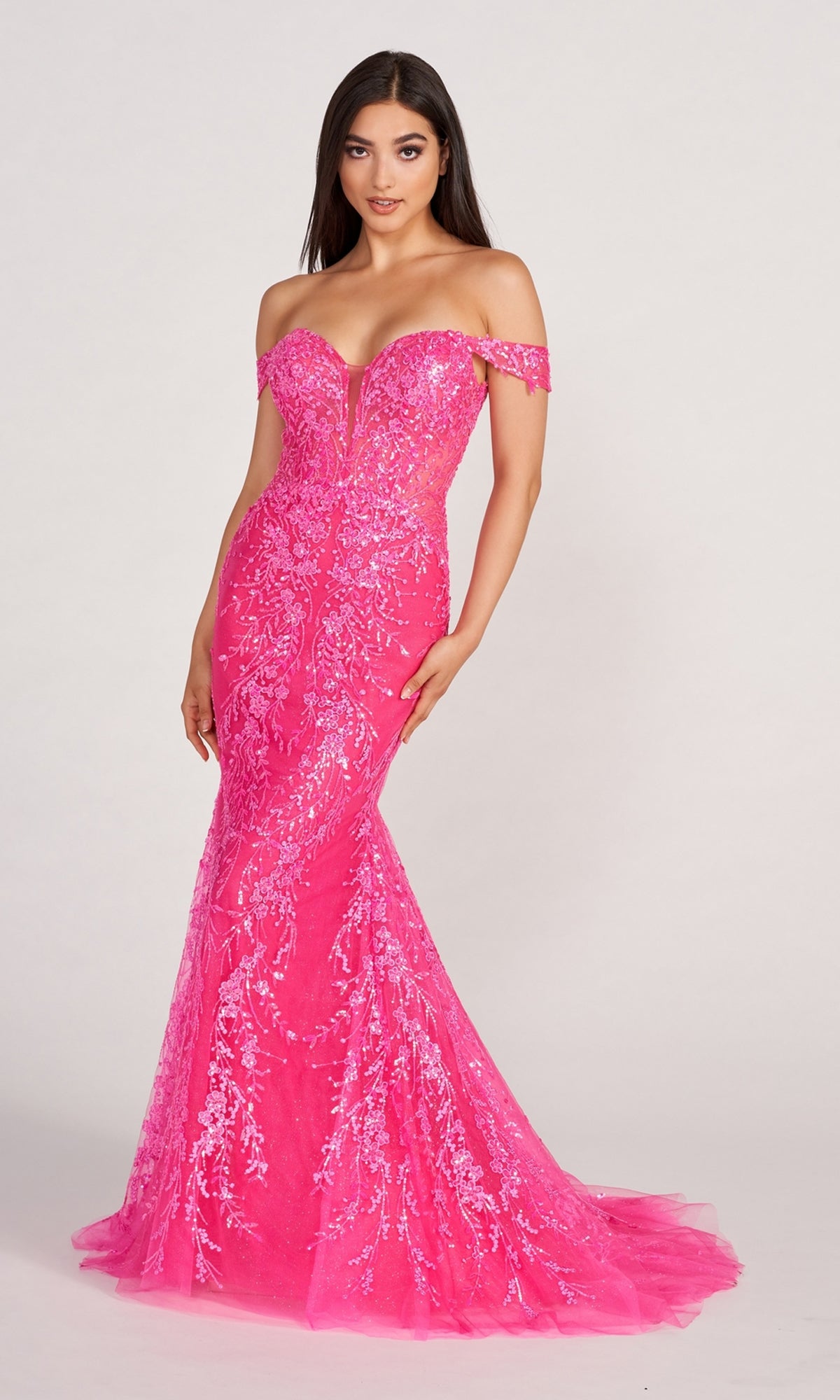 A woman poses against a plain light background in a vibrant pink Lace-Embroidered Off-Shoulder Long Mermaid Gown, adorned with sequin embellishments and a floor-length silhouette.
